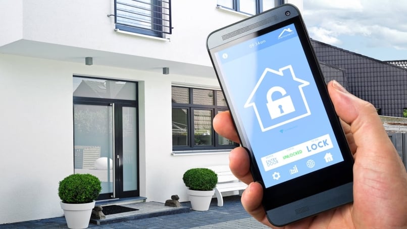 A person uses his smartphone with smarthome security app to unlock the door of his house.
